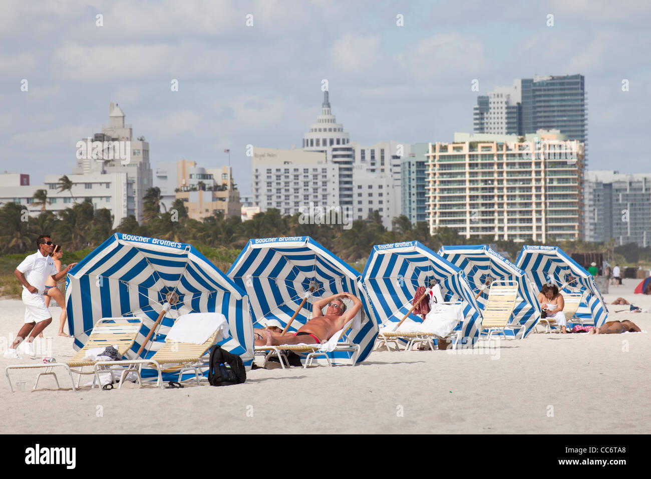 Los turistas con la sombrilla en la playa con el horizonte de South Beach, Miami, Florida, EE.UU. Foto de stock