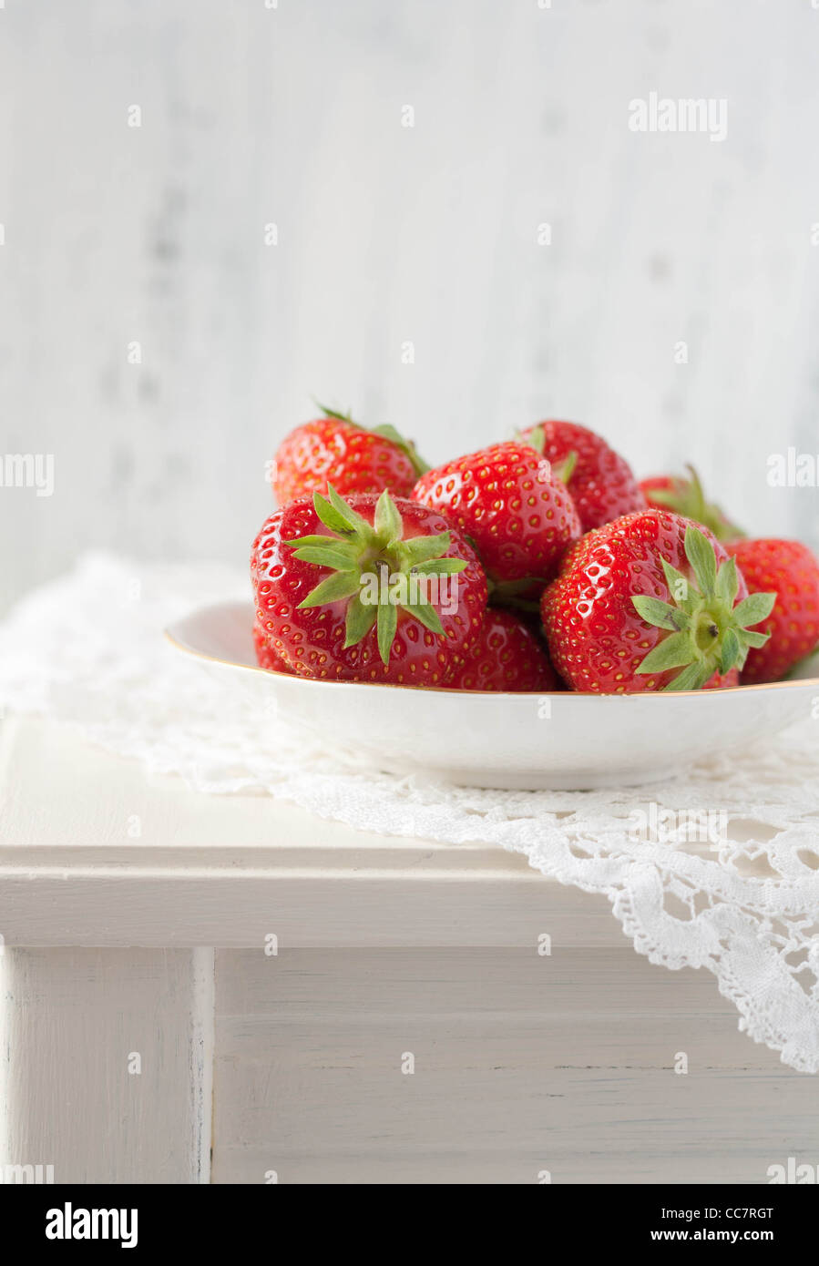 Las fresas en un cuadro blanco con una alfombra de ganchillo Foto de stock