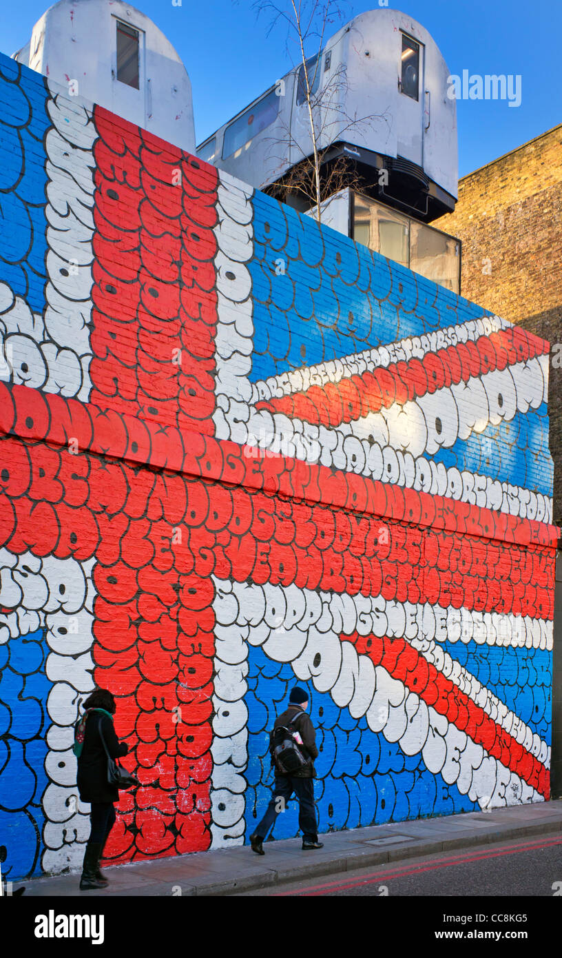 Los londinenses a pie de obra en Shoreditch delante de una imagen de la bandera de la Unión en la burbuja de cartas Foto de stock