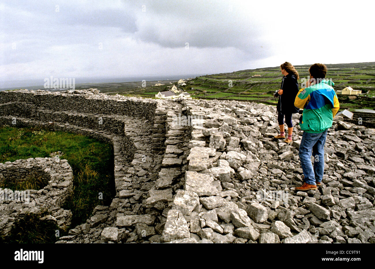Dos visitantes explorar uno de una serie de fortalezas de la Edad del Hierro en las Islas Aran. Este está en el INIS Oirr Foto de stock