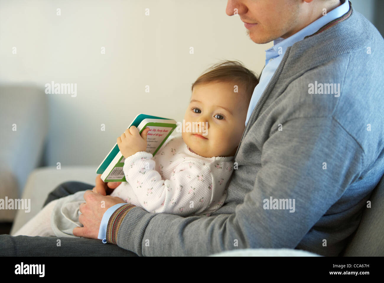 Niña sentada en el Regazo de padre Foto de stock