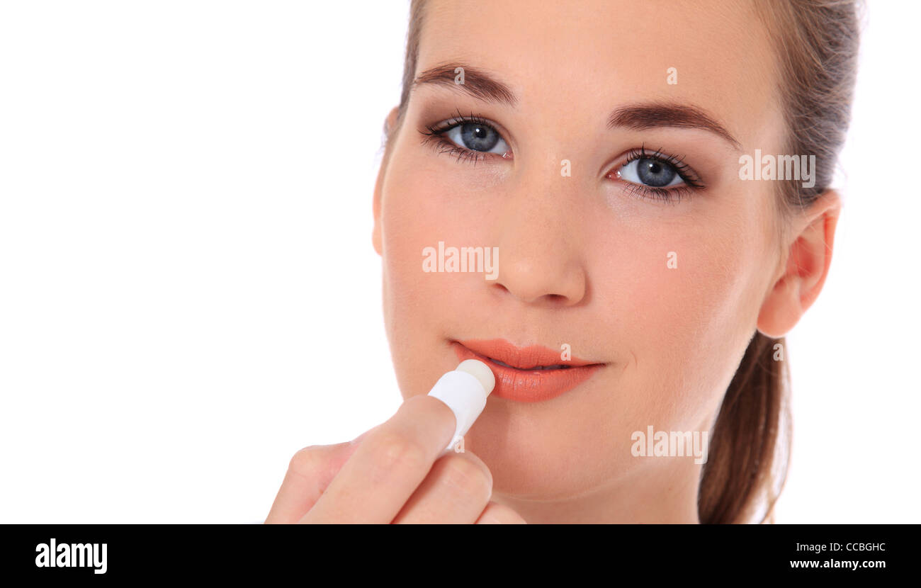 Atractiva mujer joven utilizando bálsamo labial. Todo sobre fondo blanco. Foto de stock
