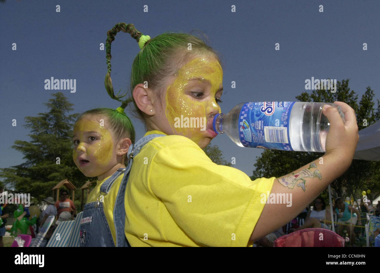 (L-R) vestida como mazorcas de maíz gemelos Christina y Alexis Yount (CQ), 4 de Brentwood, golpearon el Brentwood calor con agua helada mientras espera por su hermano para entrar en un concurso de comer maíz en la 12ª edición CornFest en Brentwood, California, el sábado, 10 de julio de 2004. Además del concurso el 3 d Foto de stock