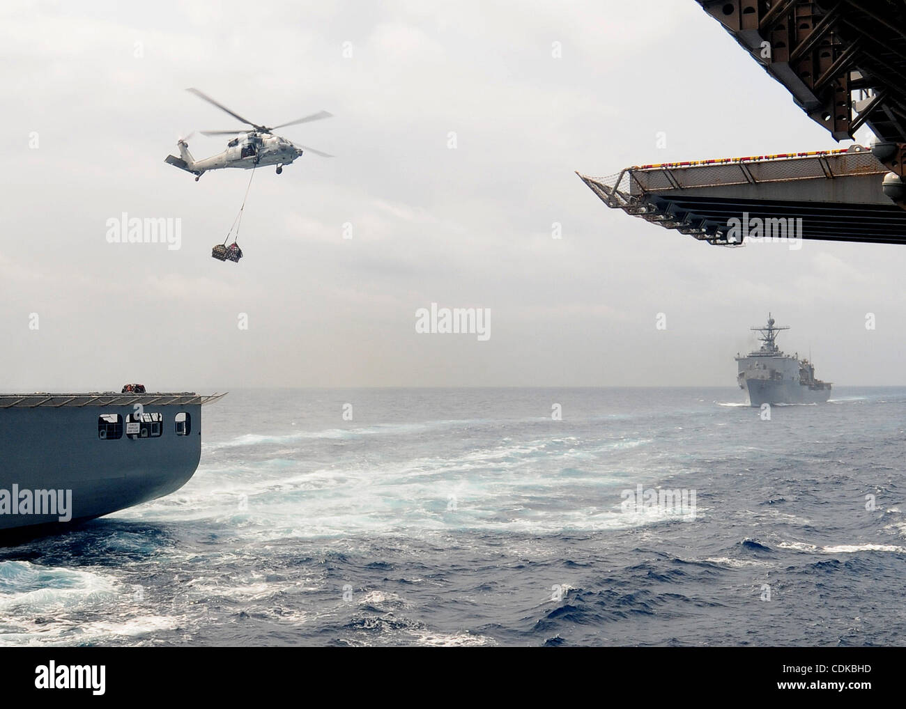El 15 de marzo, 2011 - Japón - 110315-N-5538K-183 mar Filipino (Mar. 15, 2011) un MH-60S Sea Hawk helicóptero desplaza la asistencia humanitaria y de socorro en casos de desastre los suministros procedentes de la carga seca/municiones buque USNS Matthew Perry (T-AKE 9) desplegadas en el buque de asalto anfibio USS Essex (LHD 2) durante Foto de stock