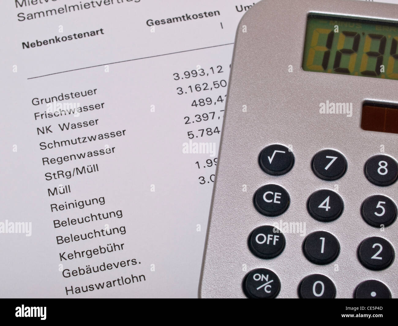 Ein Taschenrechner liegt auf einer Nebenkostenabrechnung | una calculadora de una contabilidad de cargos por servicio Foto de stock