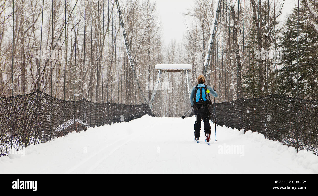 Una mujer Tawks-Foster cruzando el puente colgante sobre el río cerca de hotel Methow Mazama, Washington, EE.UU. Foto de stock