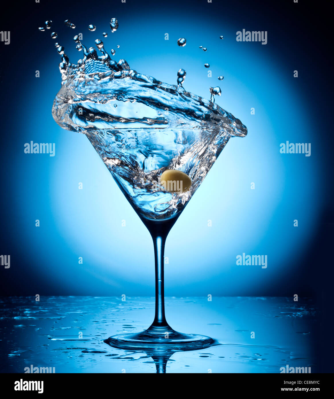 Splash martini de volar las aceitunas. Objeto sobre un fondo azul. Foto de stock