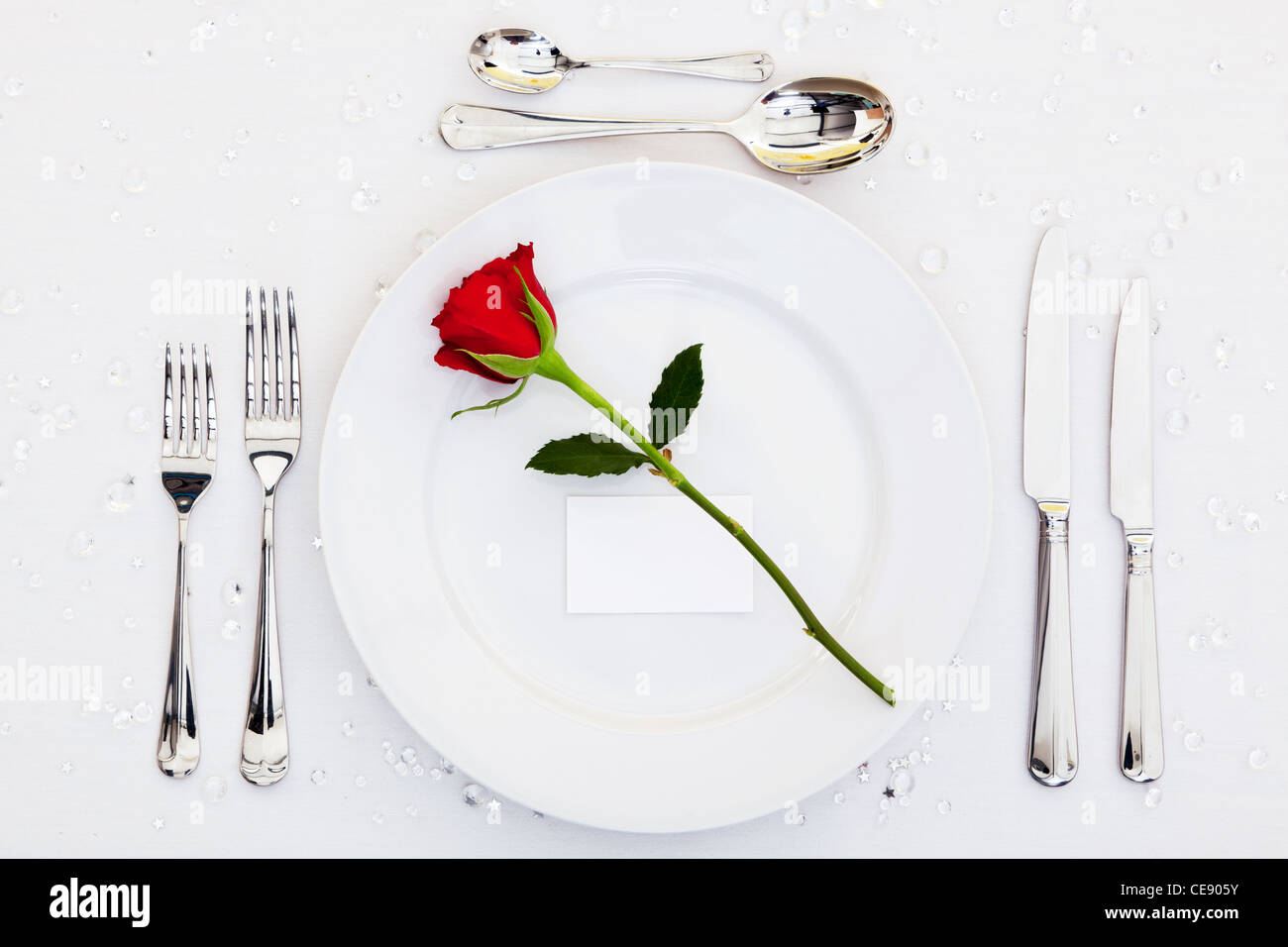 Foto de una tabla lugar con una rosa roja y tarjeta en blanco en la placa. Añadir su propio mensaje para la tarjeta de lugar. Foto de stock