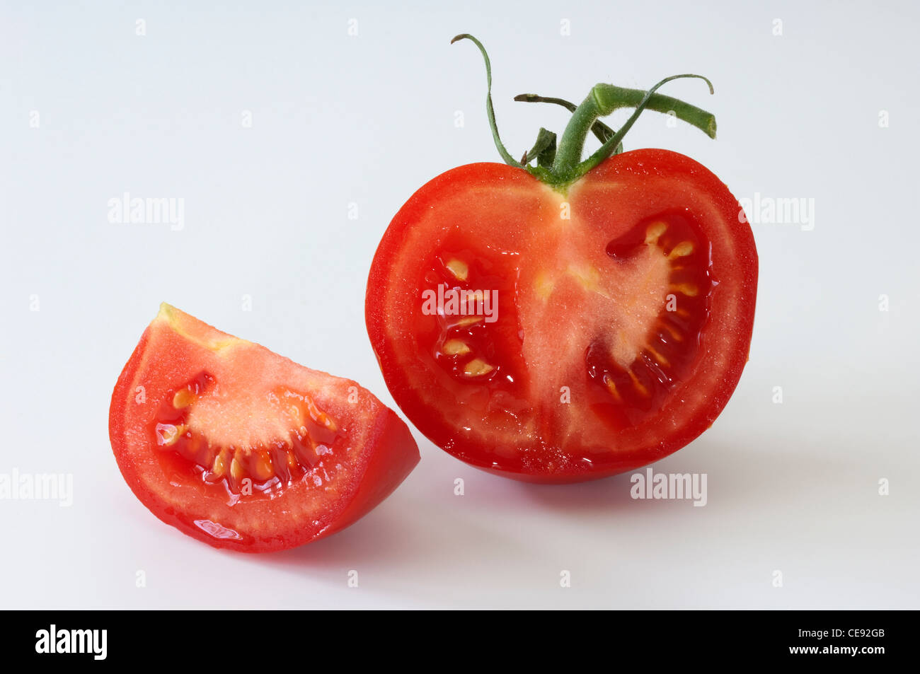 Tomate (Lycopersicon esculentum), reducido a la mitad la fruta. Studio picture contra un fondo blanco. Foto de stock