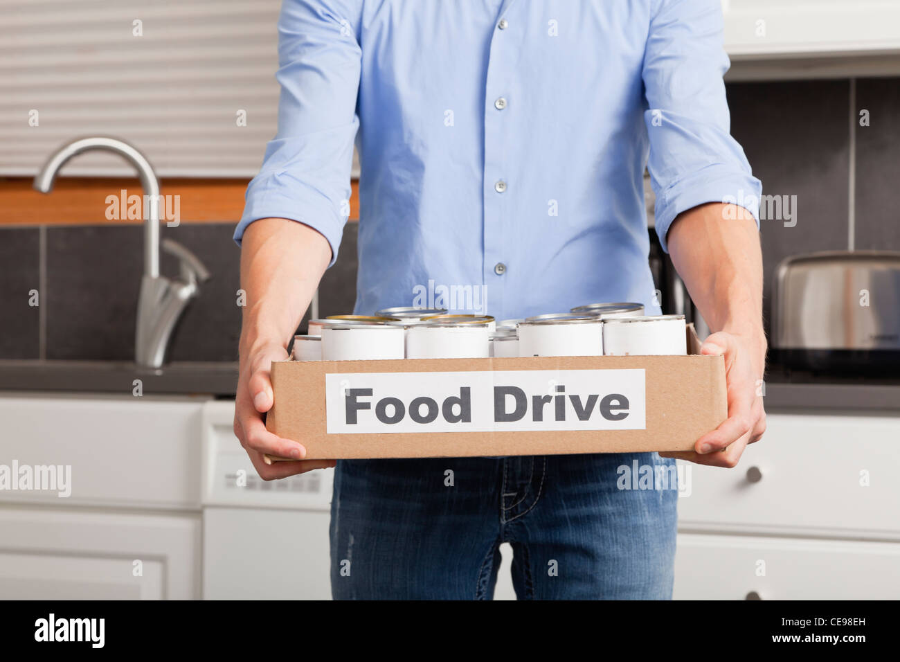 Estados Unidos, Illinois, Metamora, Hombre sujetando la caja de cartón con los alimentos enlatados en la cocina Foto de stock