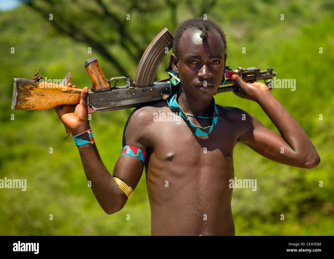 Tsemay Joven con abalorios joyas llevar rifle Kalashnikov sobre Sus hombros  Etiopía Fotografía de stock - Alamy