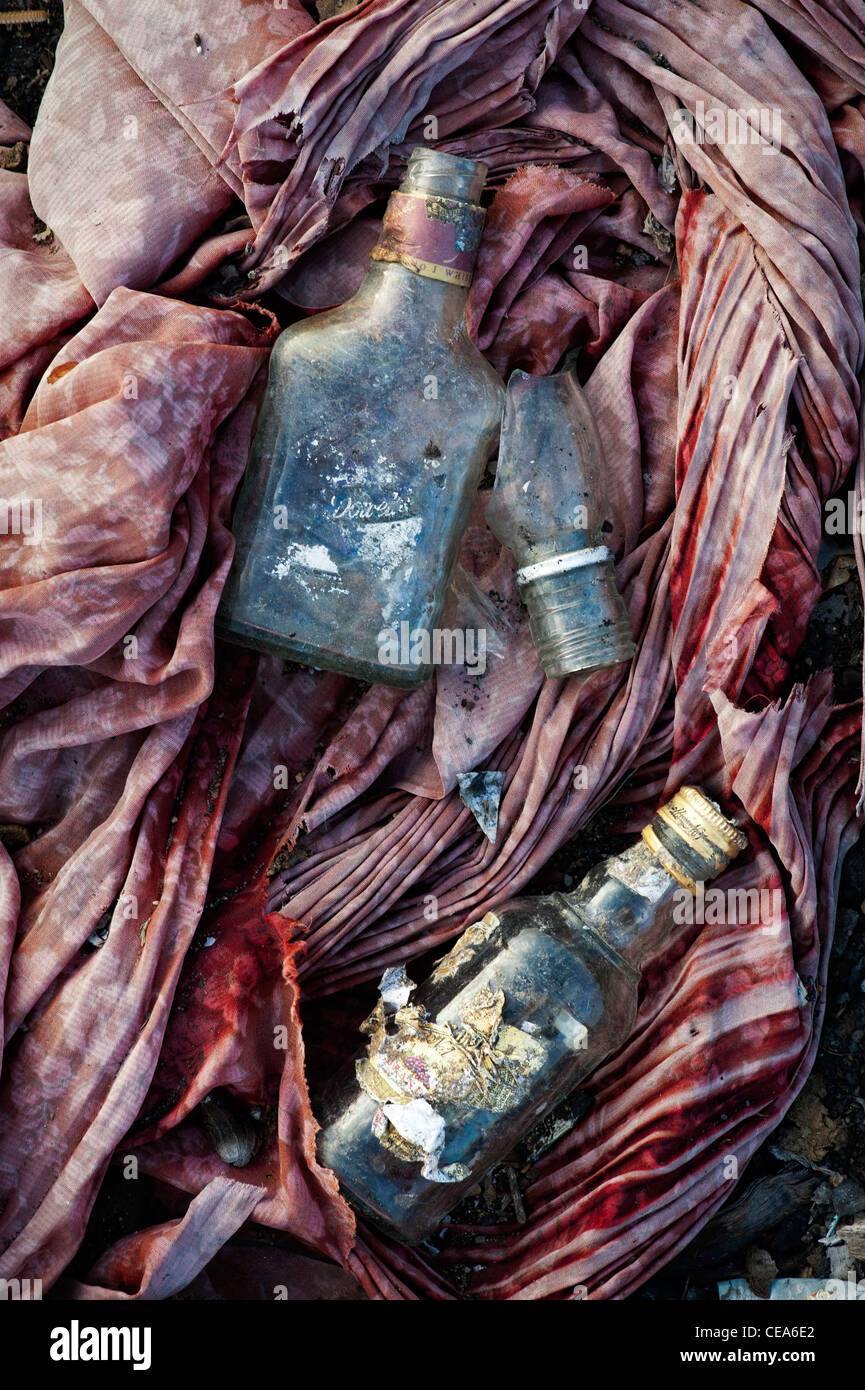 Desechado de vidrio botellas de bebidas whiskey sobre residuos de material de tela en la India rural. En Andhra Pradesh, India Foto de stock