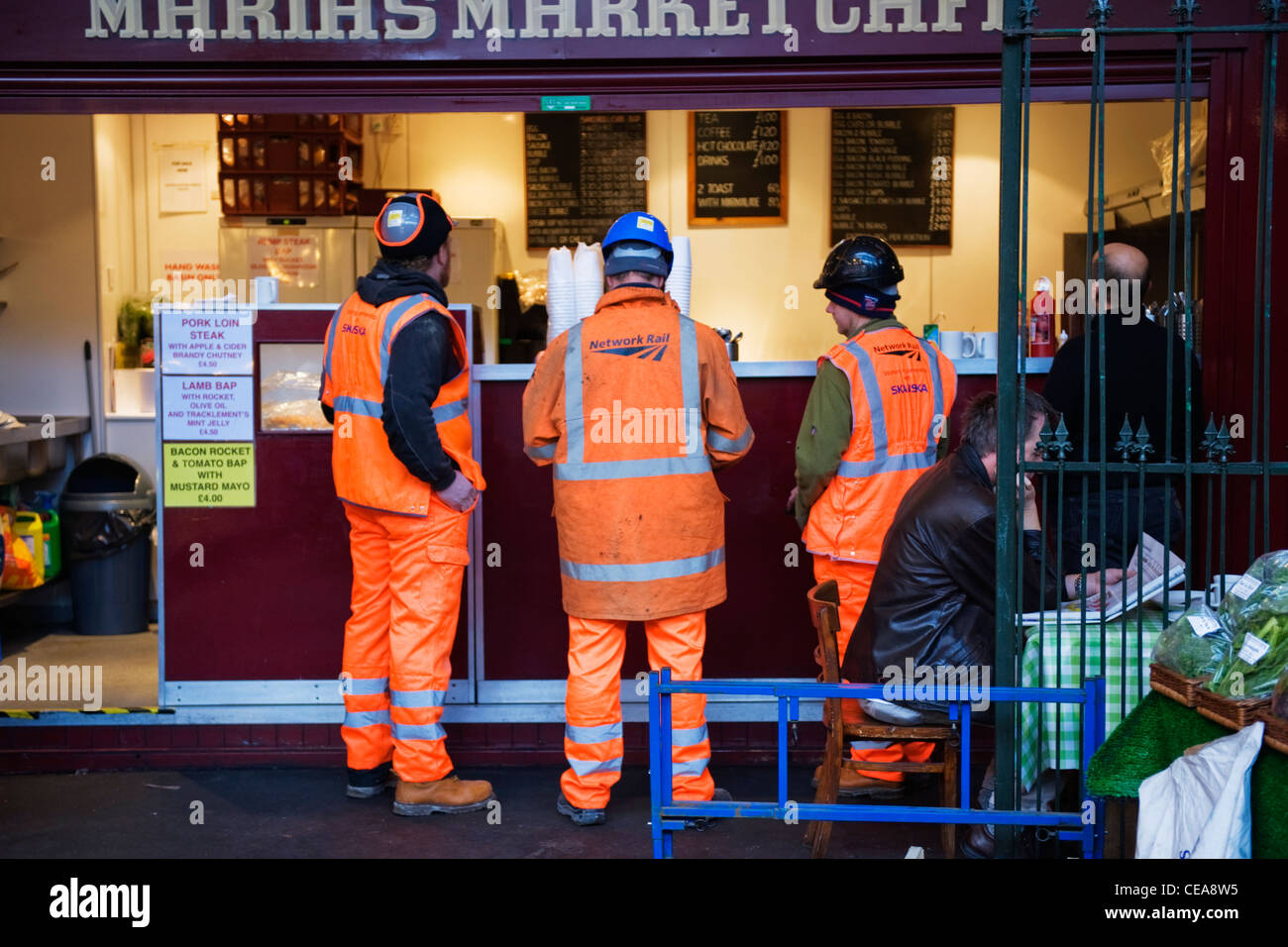 Borough Market Londres Maria's Market Cafe 3 tres trabajadores resplandor día naranja de alta visibilidad chaquetas pantalones cola para el desayuno menú pizarra pizarra Foto de stock