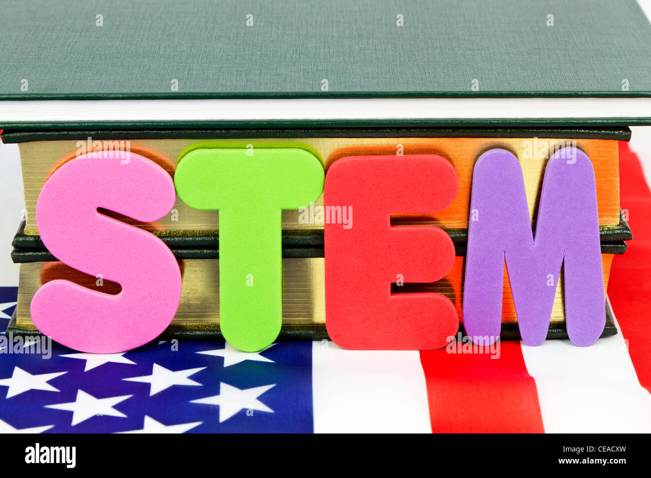 Las letras S, T, E, M, colocado antes de libros y sobre la bandera americana que representa la ciencia crítica e ingeniería. Foto de stock