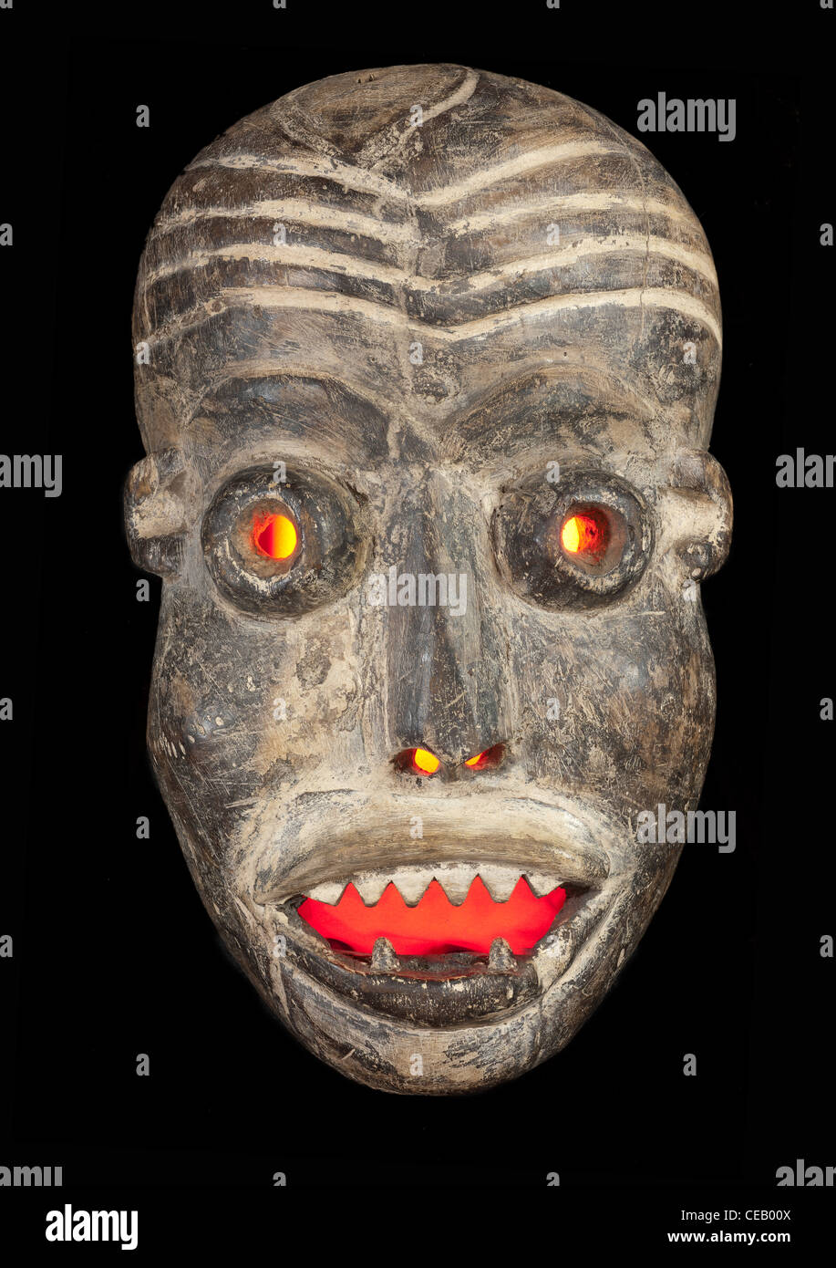 Máscara tribal africano de madera tallada, madera oscura con la cara pintada. Aislado sobre fondo negro. Congo, África Foto de stock