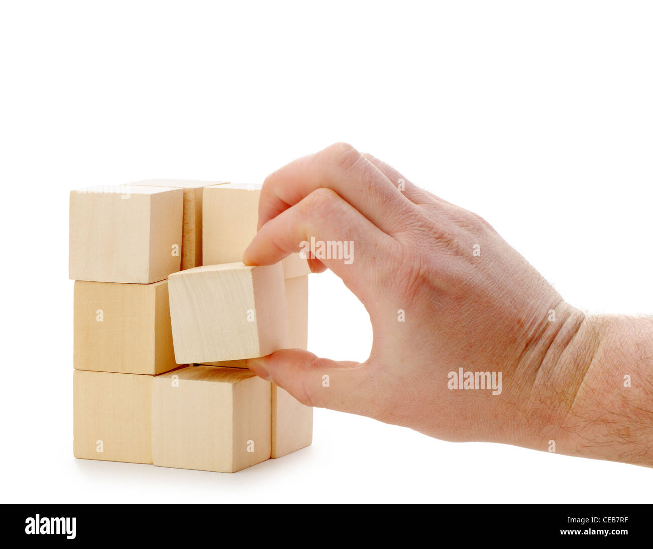 La mano se establece un cubo de madera. Se encuentra aislado en un fondo blanco. Foto de stock