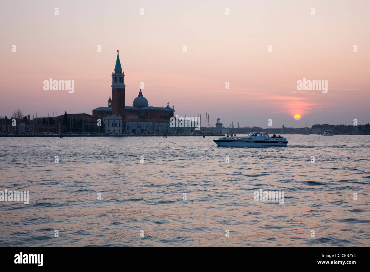 Venecia, Véneto, Italia. Vista del atardecer en laguna de la Chiesa di San Giorgio Maggiore, barco pasando. Foto de stock