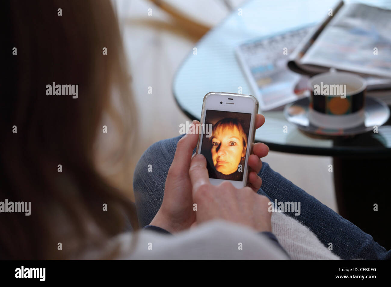 La mujer en el hogar mostrando fotografías en iPhone, Smartphone, close-up, se centran en el teléfono, REINO UNIDO Foto de stock