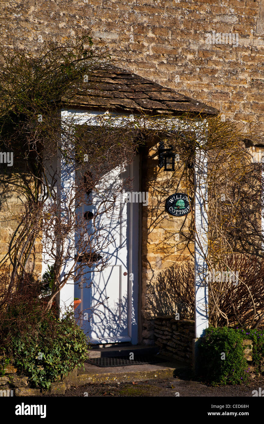 Porche con frontones y blanco puerta fornt típicas de una cabaña de piedra de Cotswold en invierno. Foto de stock