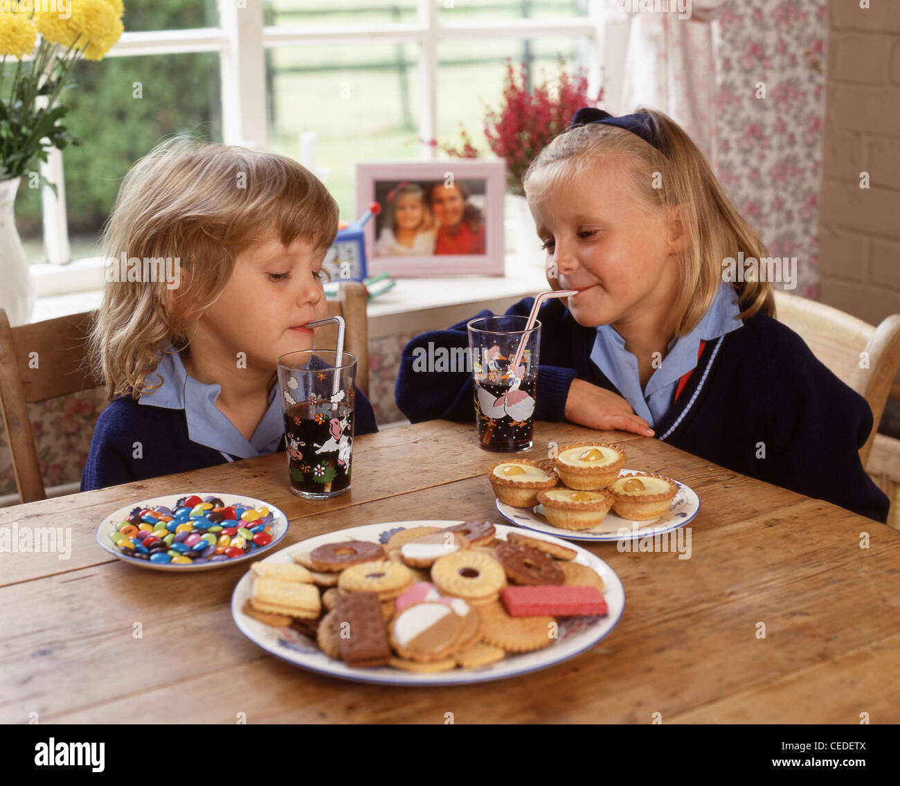 Hermanas comer galletas y beber refrescos, Berkshire, Inglaterra, Reino Unido Foto de stock