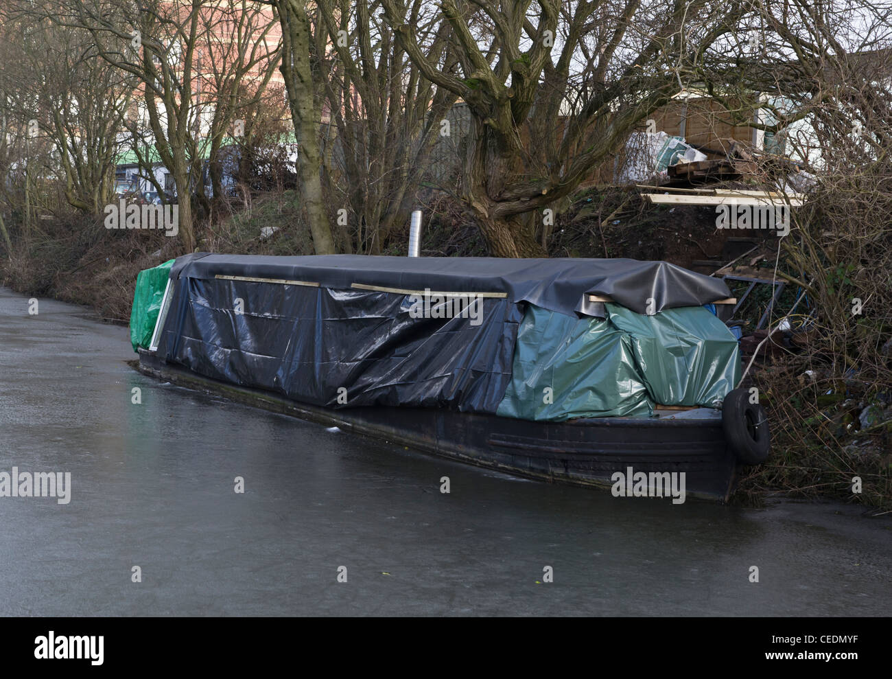 Canal angosto barco cubierto en láminas protectoras en un canal congelado Foto de stock