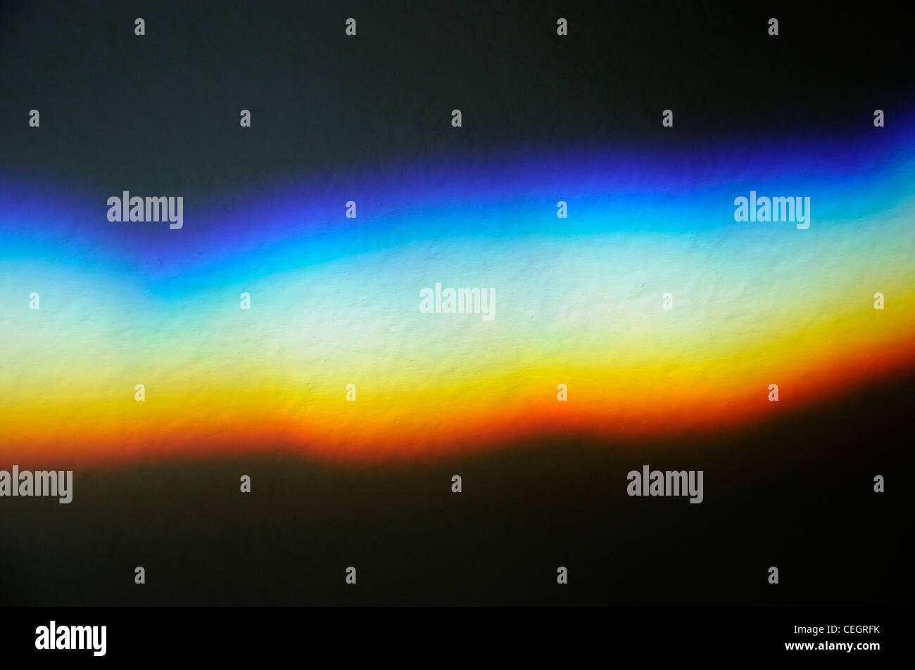 Un espectro de colores provocado por la luz refractada a través del cristal en la pared. Foto de stock