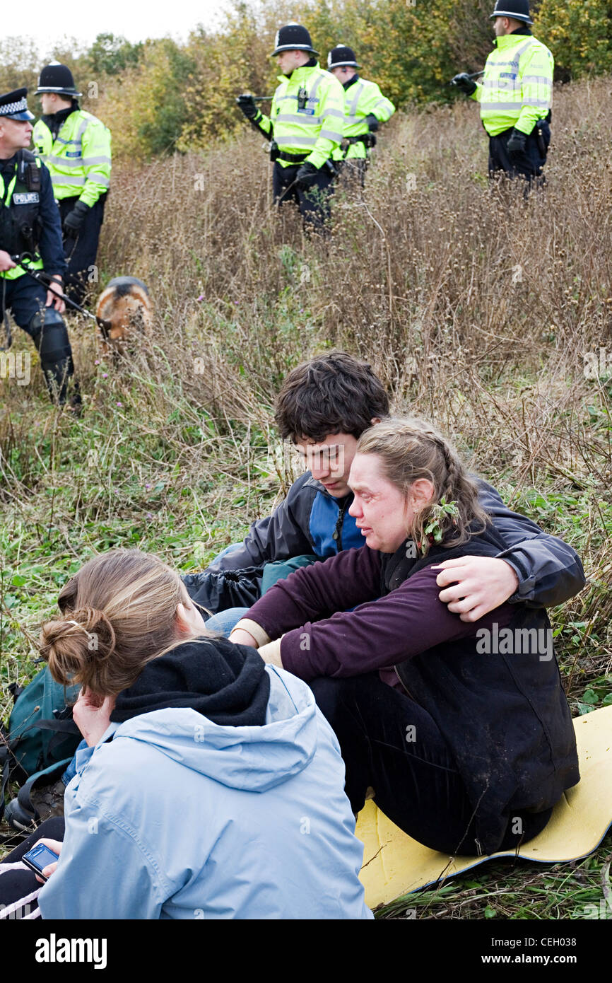 Activista de los derechos de las mujeres llorando y ser consolada por un manifestante, macho con oficiales de policía en el fondo al clima Swoop Foto de stock