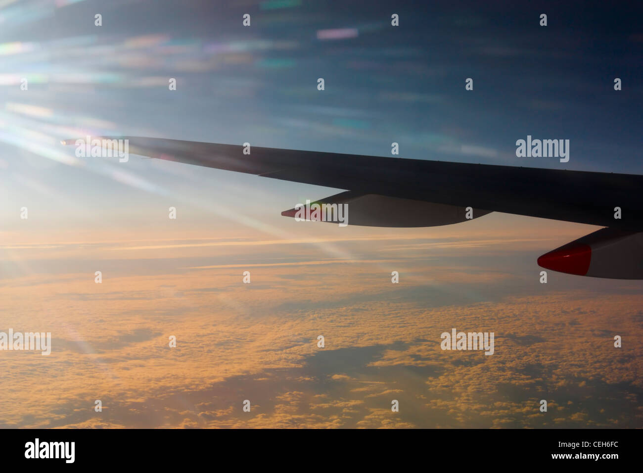 Vista desde la ventana de su asiento del ala de avión sobre la capa de nubes al atardecer Foto de stock