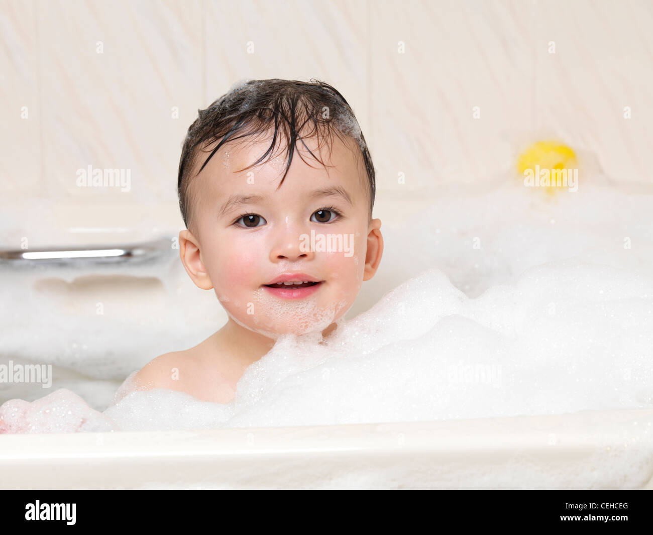 Lindo bebé de dos años disfrutando de un baño de burbujas Foto de stock