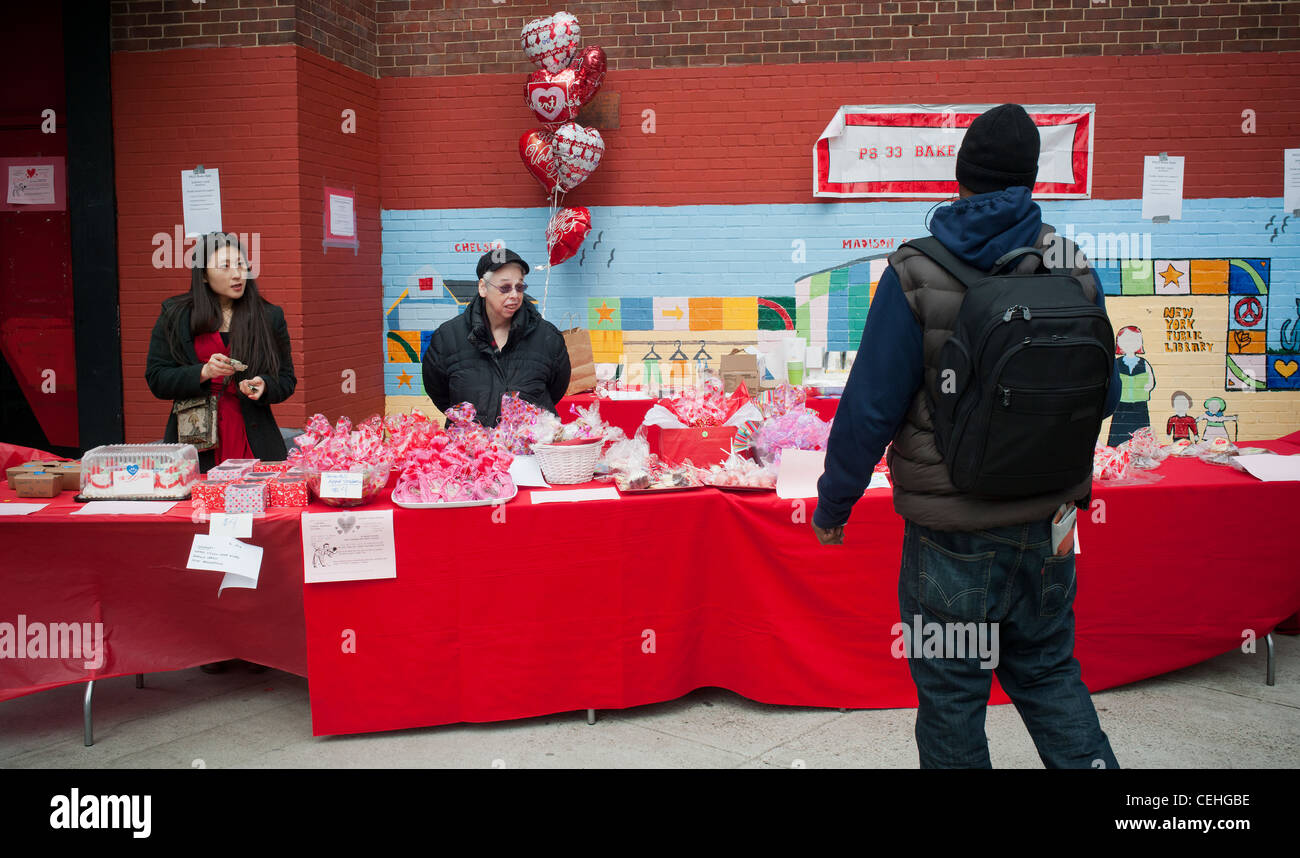 Los voluntarios del hombre una venta de pasteles para recaudar fondos para una escuela pública en Nueva York Foto de stock