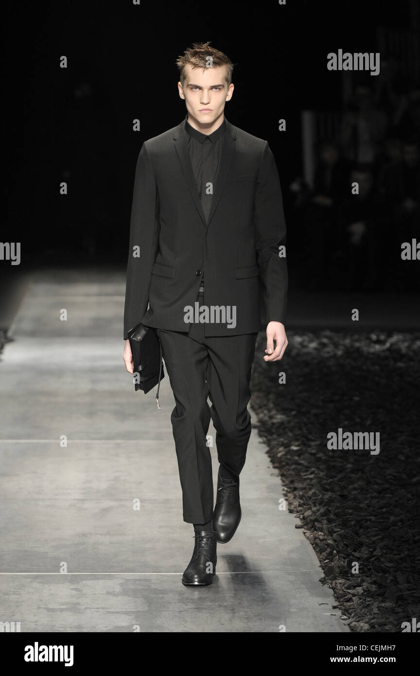 París DiHomme listo para ponerse ropa de otoño invierno traje pantalón camisa negra, corbata negra, botines negros, sosteniendo un Fotografía de stock - Alamy