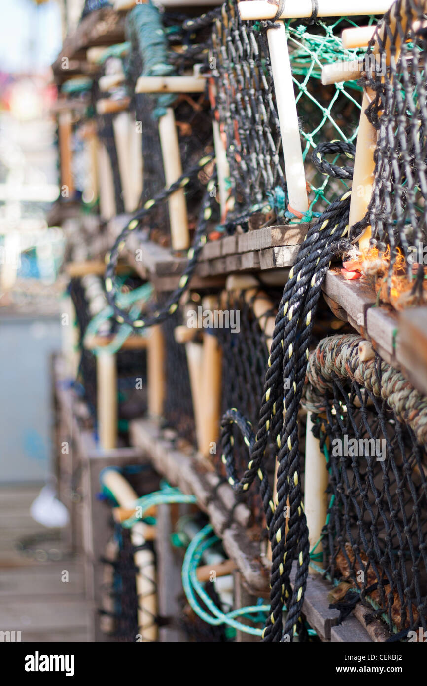 Langosta, cangrejo y redes de pesca y ollas apilados vacíos y listos para su uso por los pescadores en la industria pesquera. Foto de stock