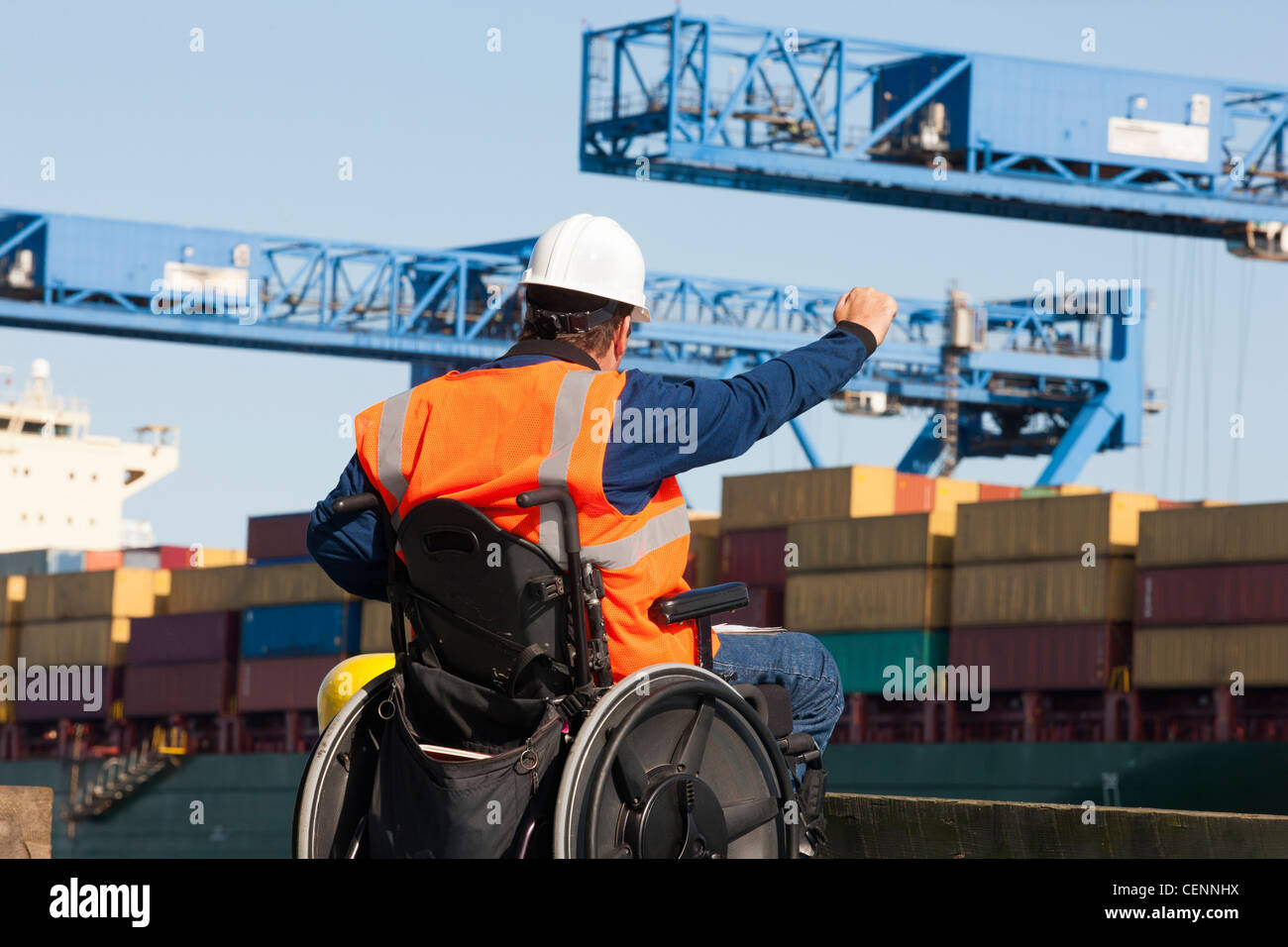 Ingeniero de transporte en silla de ruedas dando indicaciones a los contenedores en el puerto de embarque Foto de stock