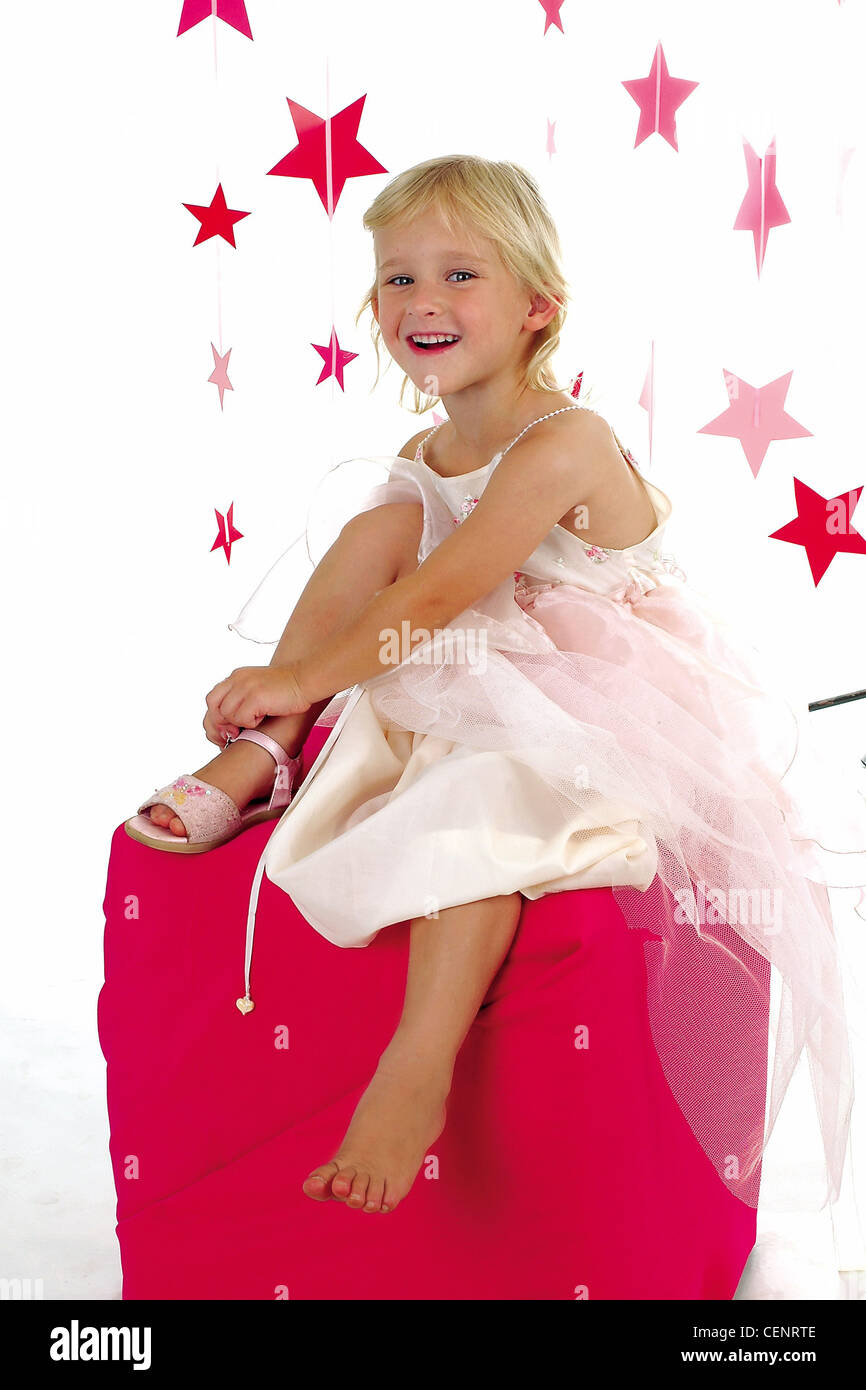 Una niña, de pelo rubio, crema vestido de fiesta, sandalias rosadas,  sentado en Rosa, rosa caja cubiertas de tela estrellas colgando en  Fotografía de stock - Alamy