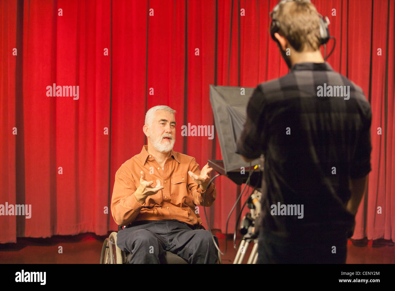 Hombre con distrofia muscular y diabetes hablando sobre una cámara en un estudio de televisión Foto de stock