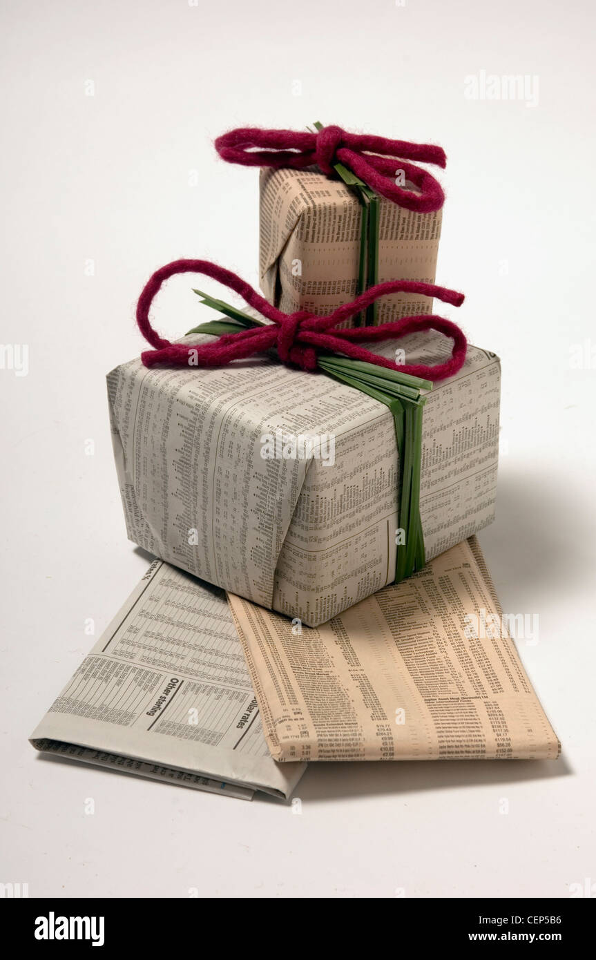 Un bodegón de regalos envueltos en papel de periódico de hierba de acero  envuelto alrededor del centro y se mantienen en su lugar por un fieltro de  Borgoña Fotografía de stock -