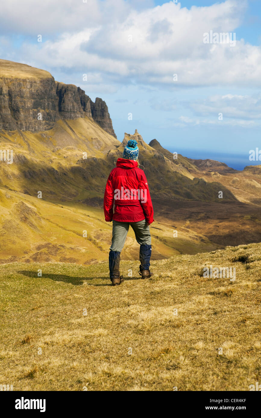 Una hembra walker llevaba un impermeable rojo mirando hacia el impresionante paisaje de la península de Trotternish desde el Quiraing. Foto de stock