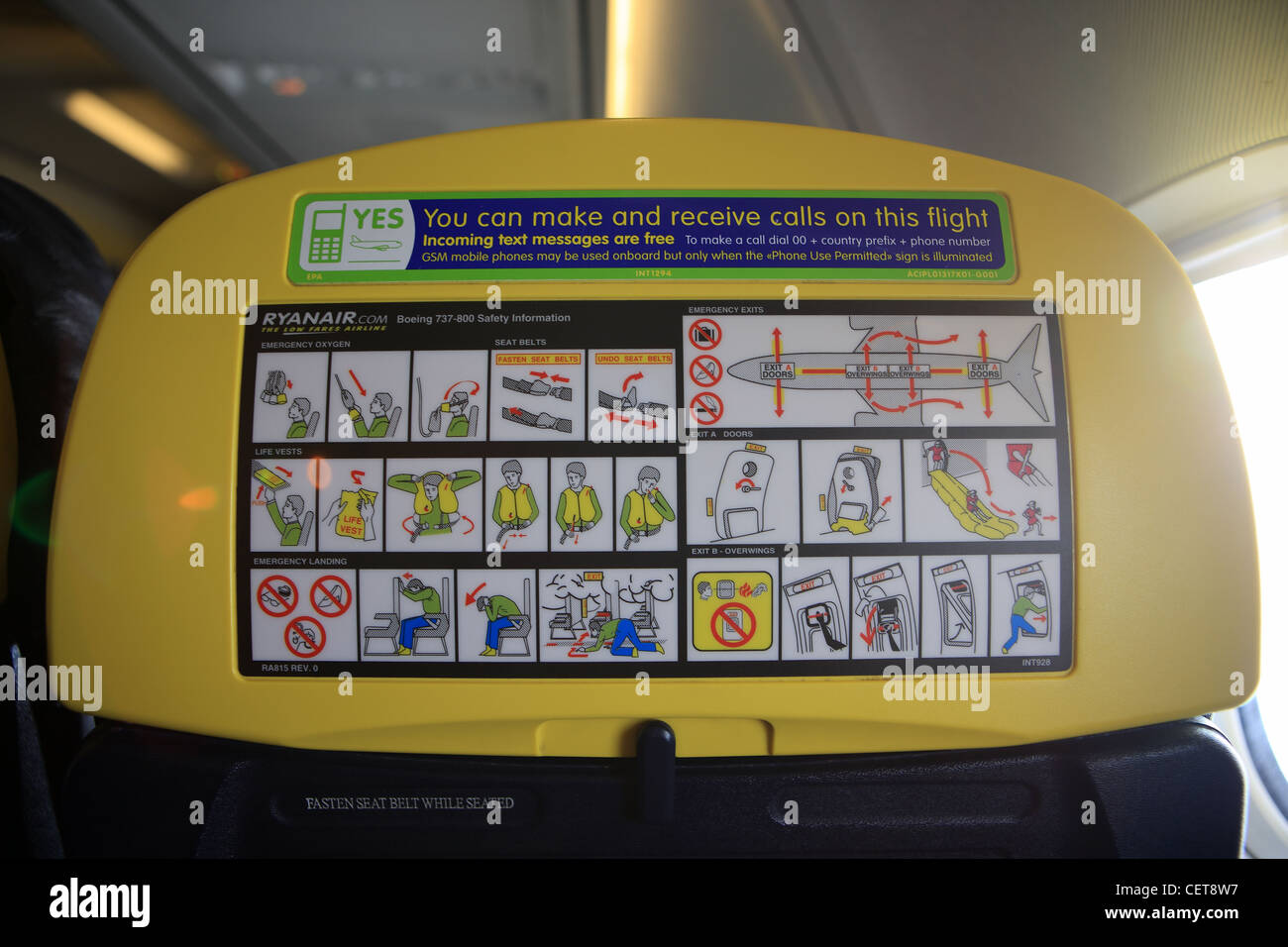 Instrucciones de seguridad y teléfono móvil en la parte posterior de los asientos de un avión de Ryanair Foto de stock