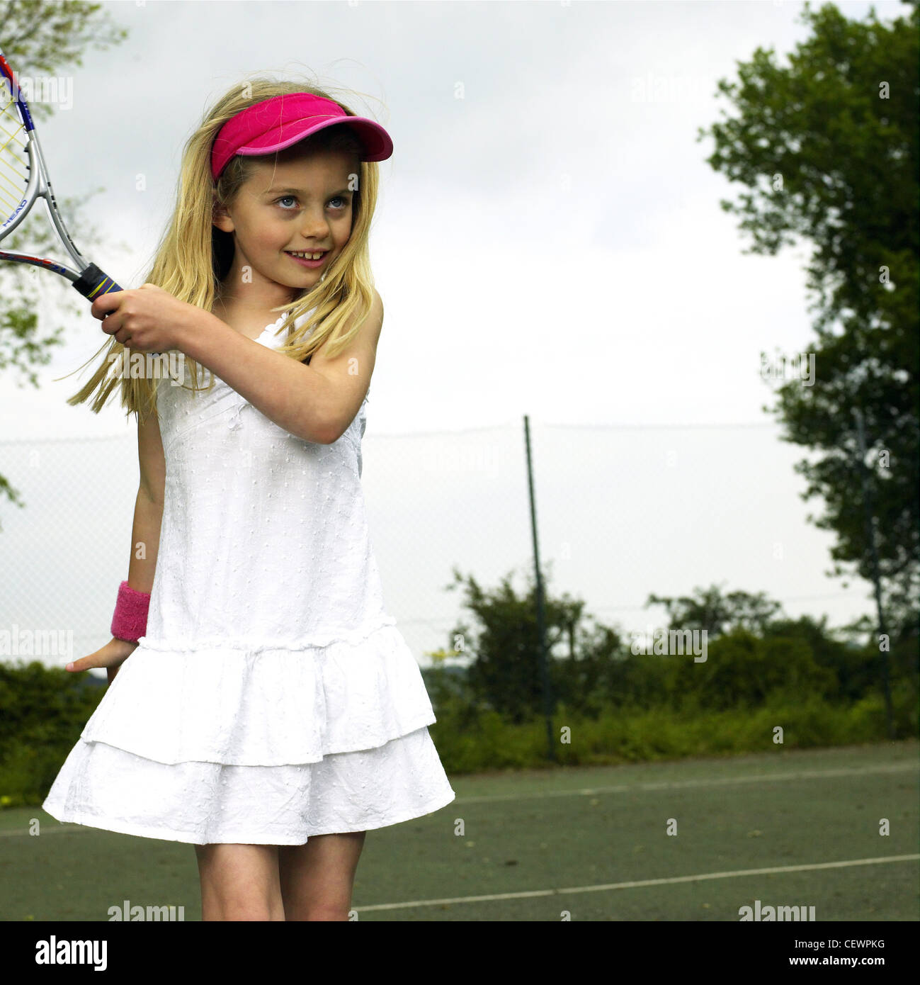 Una niña jugando al tenis vistiendo vestido blanco, rosa cap Fotografía de  stock - Alamy