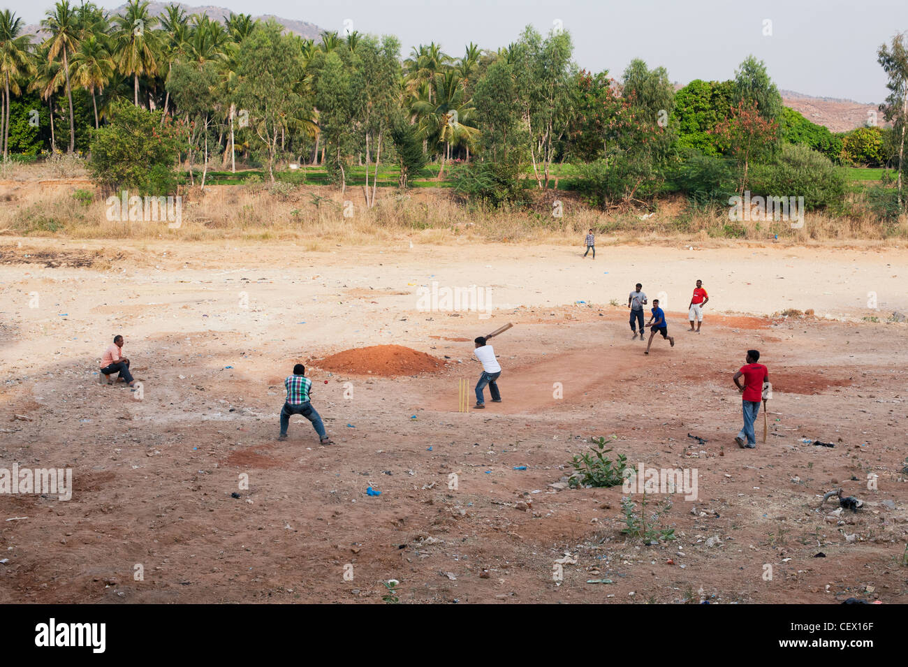 Indian muchachos jugando críquet en el lecho seco de un río en la ciudad india de Puttaparthi rural, Andhra Pradesh, India Foto de stock