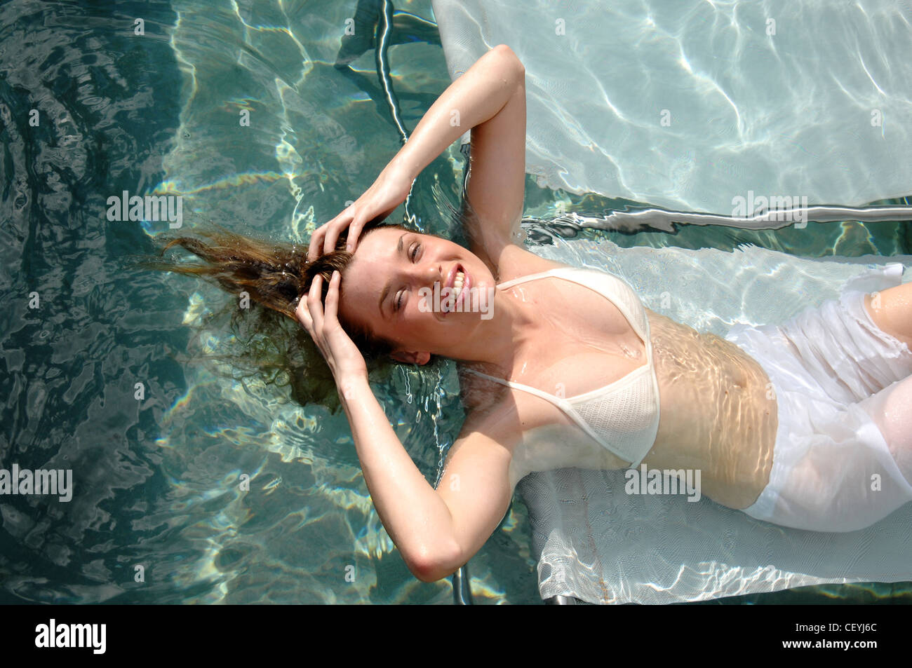 Mujeres de largo cabello rubio mojada, vistiendo bikini blanco y ver a  través de pantalones blancos, relajarse en las tumbonas de la submarina  Fotografía de stock - Alamy