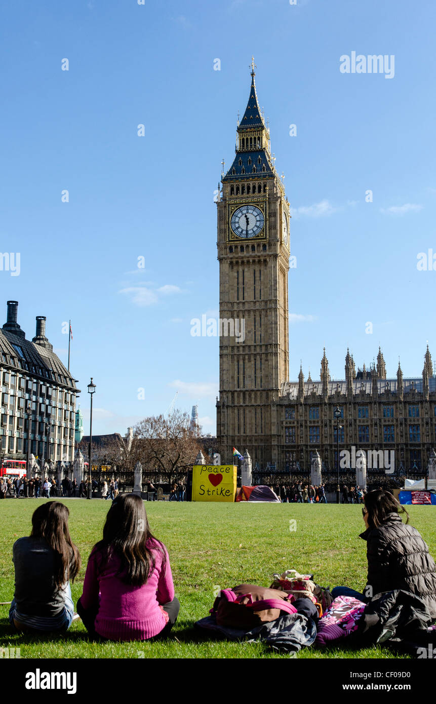 Gente sentada en un parque de la ciudad enfrente del Big Ben de Londres, Inglaterra Gran Bretaña UK Foto de stock