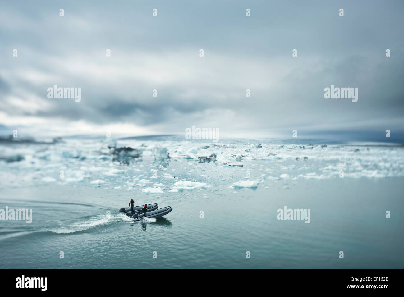 Dos hombres en un buque náuticas conducir hacia pedazos de hielo en el agua; Jokulsarlon Islandia Foto de stock