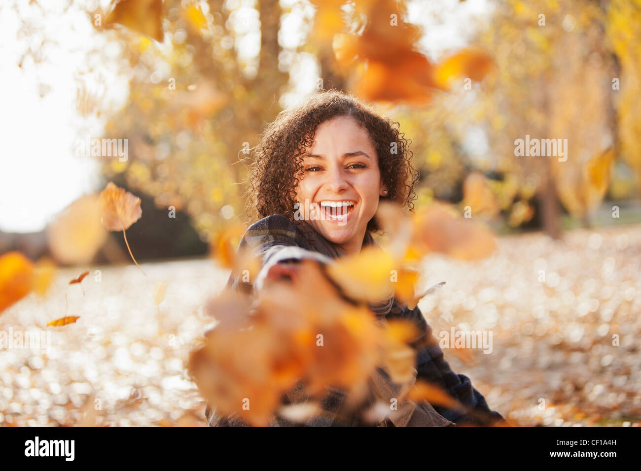 Mujer caucásica jugando en hojas de otoño Foto de stock