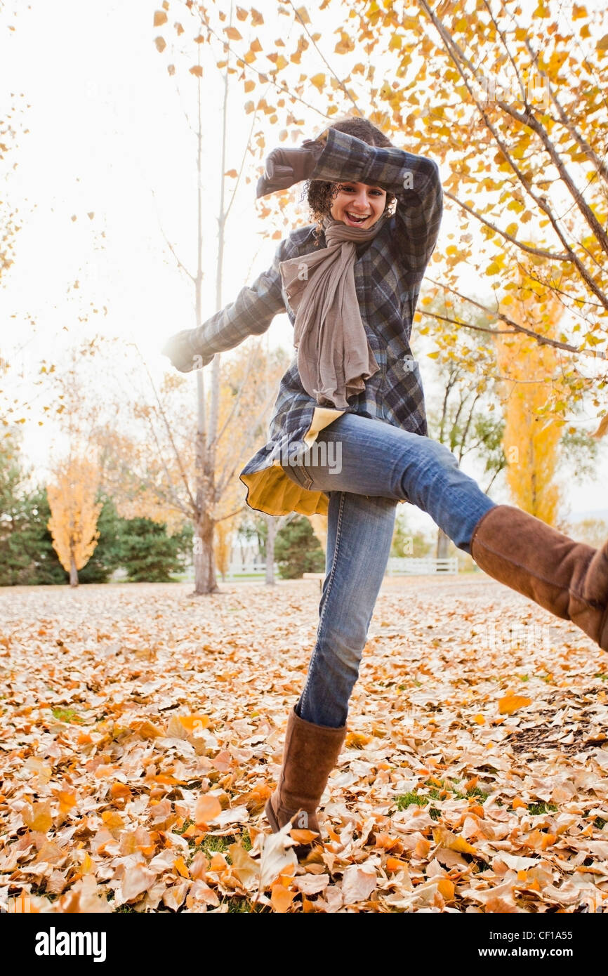 Mujer caucásica jugando en hojas de otoño Foto de stock