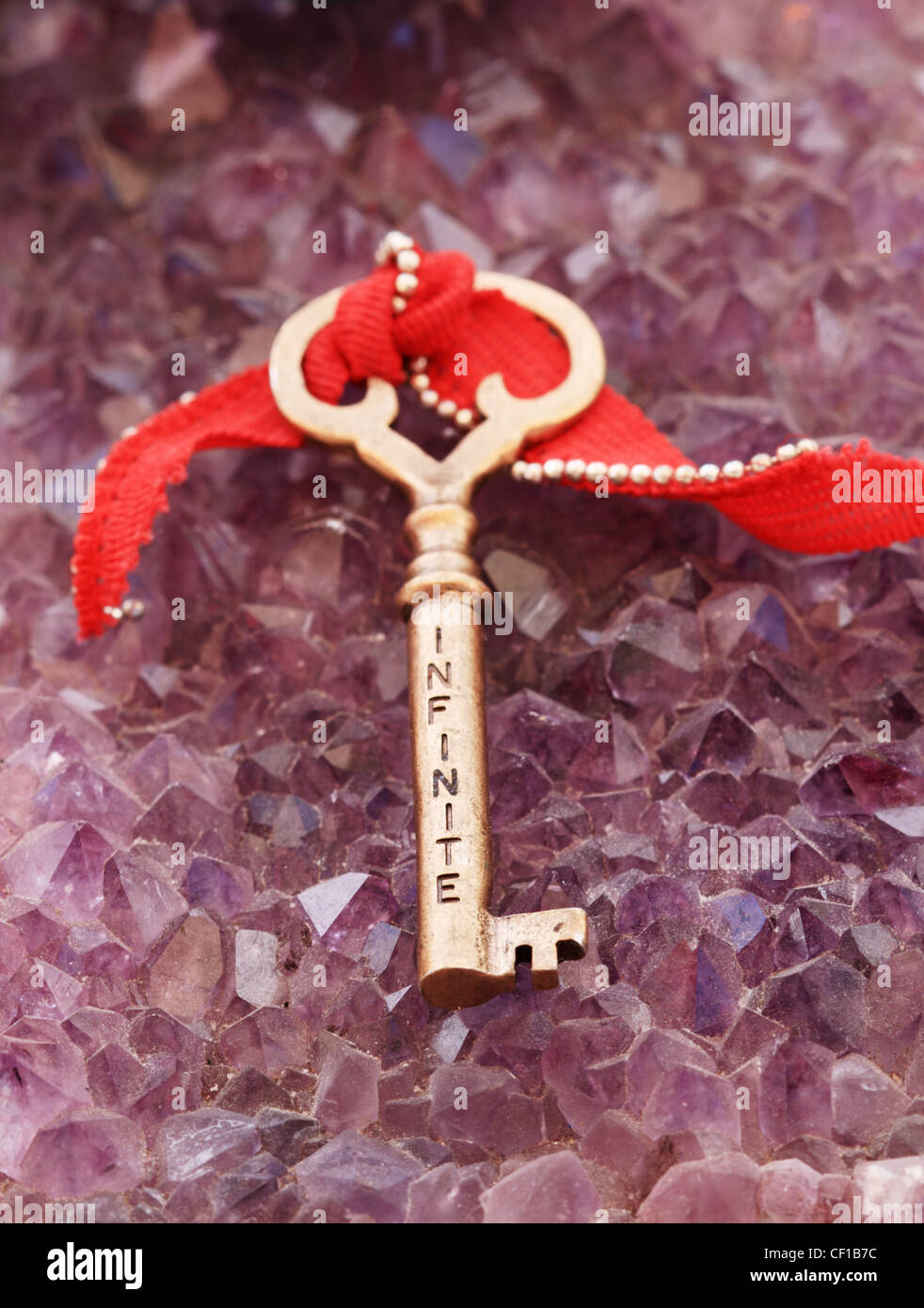 Infinito escrito en una clave antigua de bronce sentado en cristales de amatista Foto de stock