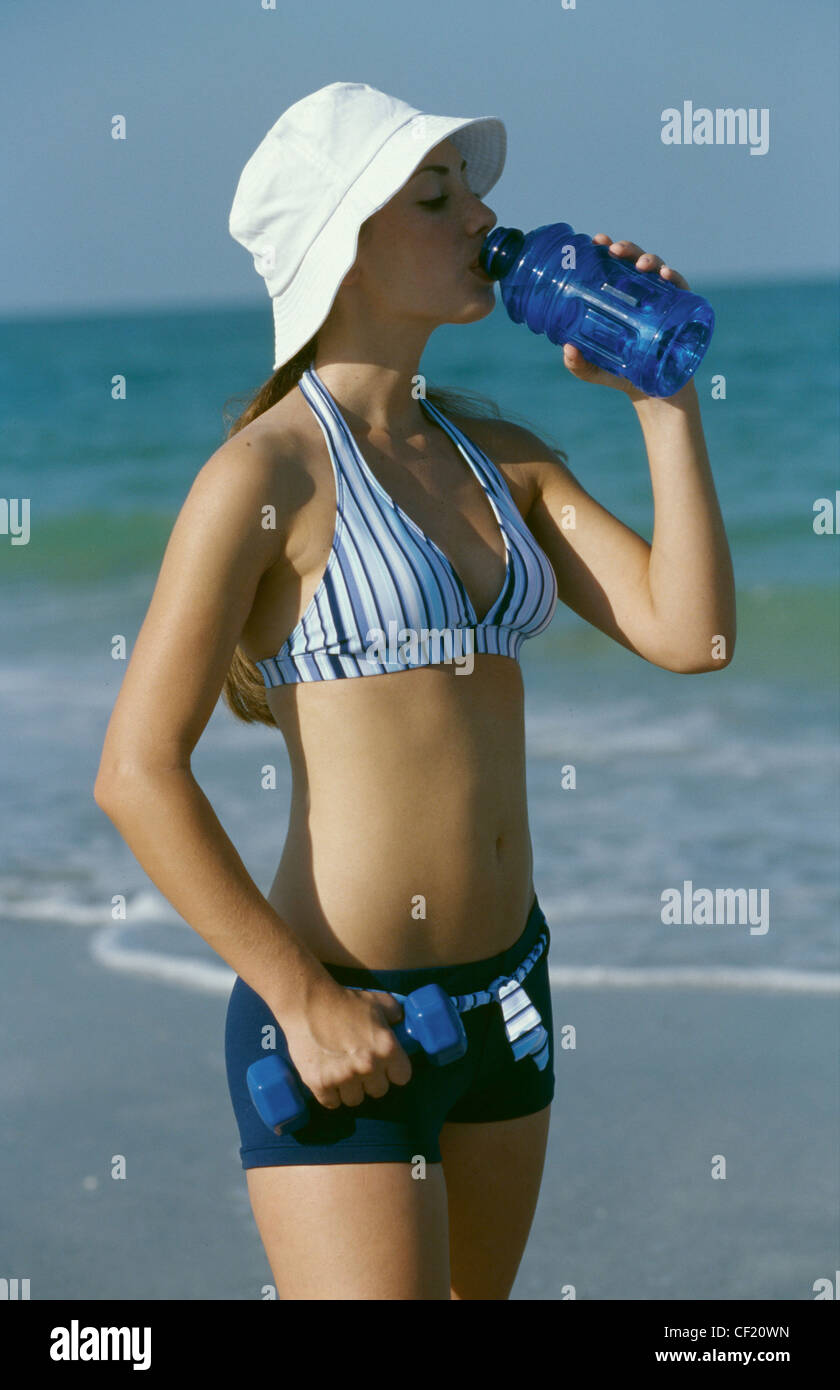 Mujeres vistiendo sombrero, rayado azul halterneck bikini y bikini azul estilo hotpants bebiendo de una botella de agua de Fotografía de - Alamy