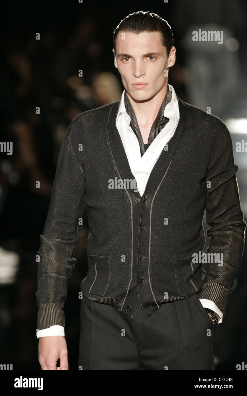 Gucci moda masculina S S macho cardigan vistiendo negro camisa blanca, con mano el bolsillo borroso fondo oscuro Fotografía de stock - Alamy