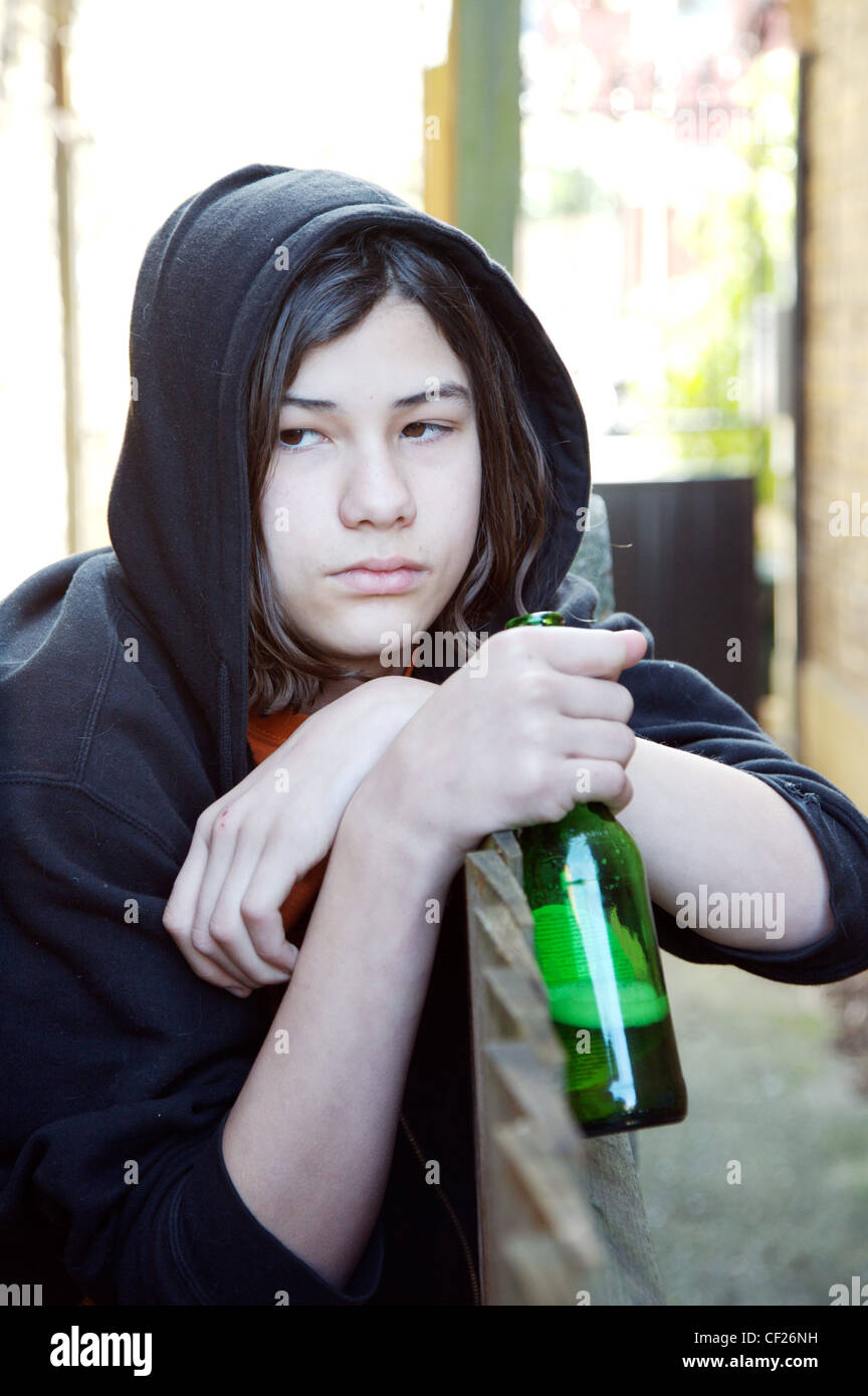 Adolescente largo cabello oscuro vistiendo negro sudadera con capucha  camiseta naranja inclinándose por encima de una valla mirando hacia abajo  al lado sujetando Fotografía de stock - Alamy