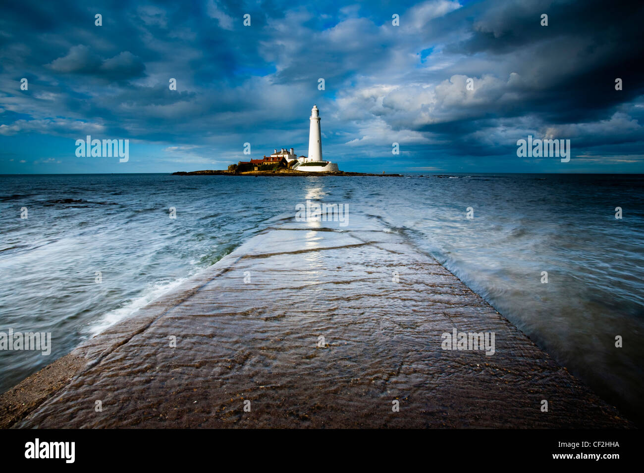 Marea entrante envuelve la calzada que une St Mary's Island y faro para el continente. Foto de stock